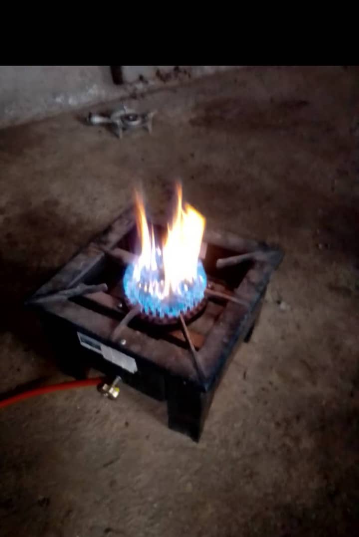 La flamme d'un réchaud alimenté au biogaz brûle dans une cuisine sombre